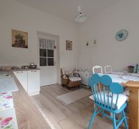 A kitchen with a wooden decor floor in a 4-room apartment with colorful chairs.
