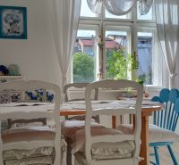 A dining room with curtains, floral decoration, and a wooden table in a 4-room apartment.