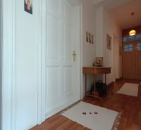 A hallway of a 4-room apartment with a wooden decor floor and white doors.