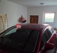 A garage in a family house with a car, windows, and stored items.