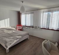 A bedroom in a family house with a bed, a nightstand, and a wooden decor floor.