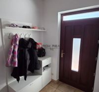 Entrance hallway in a family house with a shoe cabinet, coat hooks, and brown tiles.