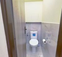 Bathroom in a recreational apartment with a toilet, paper holder, and tiles.