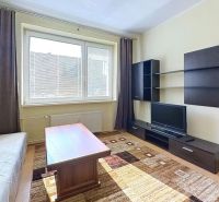 Living room in a holiday apartment with carpeted floor, sofa, and television.