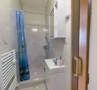 Bathroom in a Holiday Apartment with a bathtub and a sink, surrounded by light tiles.