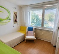 A room in a 4-room apartment with a bed, a chair, and a floor with a wooden decor.
