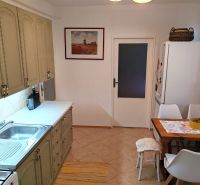 A kitchen in a 4-room apartment with a retro kitchen unit, a dining table, and ceramic flooring.