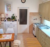 A kitchen with a dining table, white cabinets, and beige tiles in a 4-room apartment.