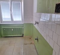 A kitchen in a 2-room apartment with white tiles and green walls.