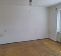 A room with white walls and a floor with a wooden decor in a two-room apartment.