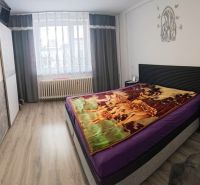 A bedroom in a family house with a wooden decor floor and a bed with a colorful blanket.