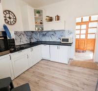 A kitchen in a family house with white cabinets and a wood-patterned floor.