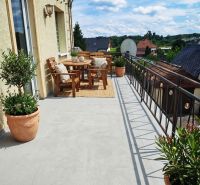 A balcony of a family house in Lakšárska Nová Ves with wooden furniture and flowers in pots.