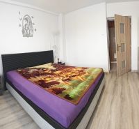 Bedroom in a family house with a bed, colorful throw, and floor with wood decor.