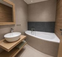 Bathroom with a bathtub, sink on a wooden countertop in a 2-room apartment.