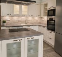 A kitchen in a 2-room apartment with a wood-patterned floor and stainless steel appliances.