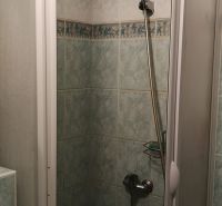 Bathroom with a tiled shower stall and a shower head in a studio apartment.