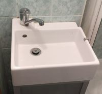 A small bathroom in a studio apartment with a sink and a shower.