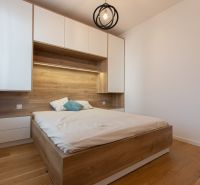 Bedroom in a 2-room apartment with a bed and storage spaces, floor with wood decor.