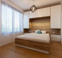 A bedroom with a bed, furniture with a wooden decor, and a large window in a two-room apartment.