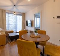 Living room with a sofa, table, and yellow chairs in a two-room apartment, floor with wooden decor.