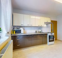 A kitchen in a 2-room apartment with a wooden decor floor and appliances.