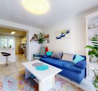 Living room with a sofa and an open kitchen in a two-room apartment with a wooden decor floor.