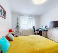 Bedroom in a 2-room apartment, bright interior, bed with a yellow throw, work corner.