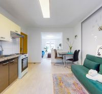 Kitchen with dining area in a 2-room apartment, floor with wood decor, green sofa.
