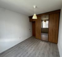 Bedroom with wood-patterned flooring and a built-in wardrobe in a three-room apartment.