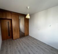 A room in a 3-room apartment with a wooden decor floor and built-in cabinets.