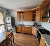 A kitchen in a 3-room apartment with a wooden decor floor and stainless steel appliances.
