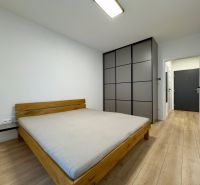 Bedroom with a bed and built-in wardrobe, floor with wood decor in a 2-room apartment.