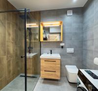 Bathroom in a 2-room apartment with a wooden decor floor and a shower corner.