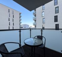 The balcony of a 2-room apartment on Jána Pavla II. in Prešov with furniture and a view of the buildings.