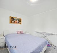 Bedroom in a 3-room apartment with a bed, painting, and ironing board.