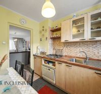 A kitchen in a 3-room apartment with classic cabinets and a dining table with decorative accessories.