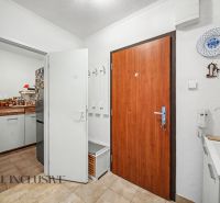 The entrance hall with light walls and a wooden decor floor leads to the kitchen.