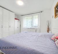 A bright bedroom in a 3-room apartment with white furniture and a decorative painting.