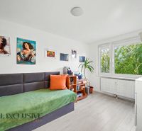 A room in a 3-room apartment with comfortable seating, wall decorations, and a large window.