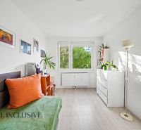 A bright room in a 3-room apartment, wooden decor flooring, simple furniture and decorations.
