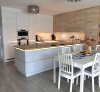 A kitchen in a family house with white cabinets and a wood-patterned floor.