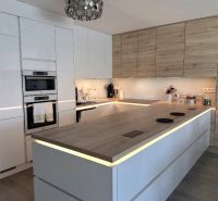 A kitchen in a family house with white cabinets and a wood-patterned floor.