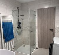 Bathroom with a shower, bathtub, washing machine, and towel in a family house.