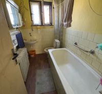 A bathroom in a family house with a bathtub and a wooden decor floor.