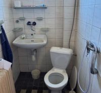 Bathroom in a family house with a sink, shower, and toilet, with soft tiles on the walls.