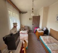 A room in a family house with beds, a dresser, a television, and curtains.