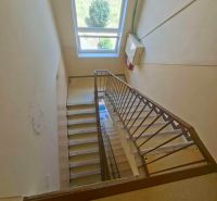 A staircase in a 3-room apartment with a large window providing an outside view.