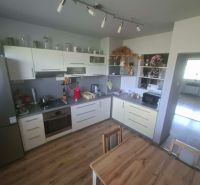 A kitchen with white cabinets and a wood-patterned floor in a 3-room apartment.