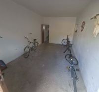 A garage with bicycles in a 3-room apartment, simple white walls and a concrete floor.
